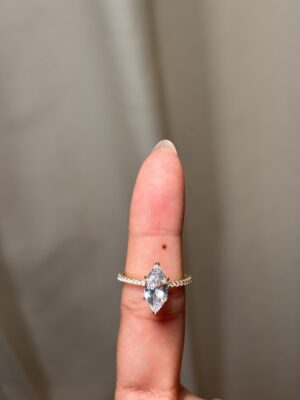 Anillo solitario con gema central corte marquise, banda pavé y halo oculto dorado