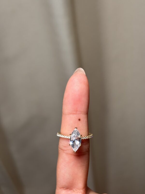 Anillo solitario con gema central corte marquise, banda pavé y halo oculto dorado